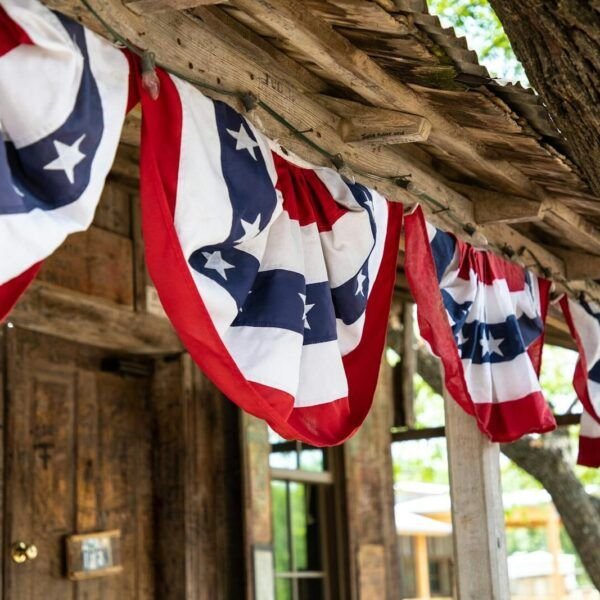 Patriotic red, white, and blue flags hang on a rustic wooden porch, showcasing American pride.